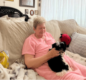 Woman in pink sitting on couch holding therapy dog